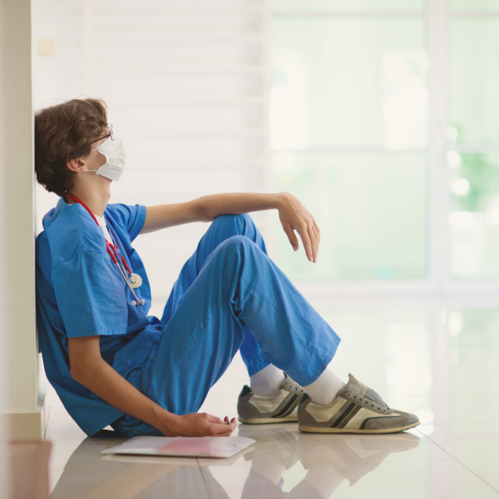 Rebuilding Empathy: Combatting Compassion Fatigue. Image of tired doctor sitting on the floor in a hospital hallway.