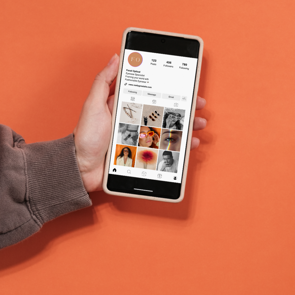 Photo of hand holding smart phone with instagram profile over an orange background